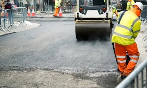 Men at work asphalting street pavement in London, UK